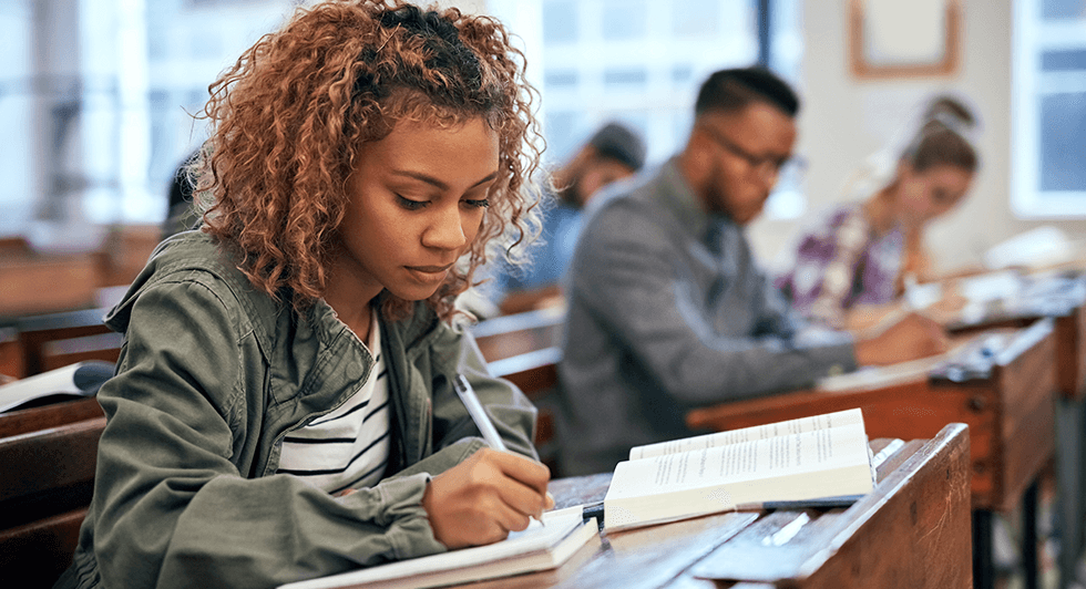 a young female student takes the SAT or ACT exam in a classroom